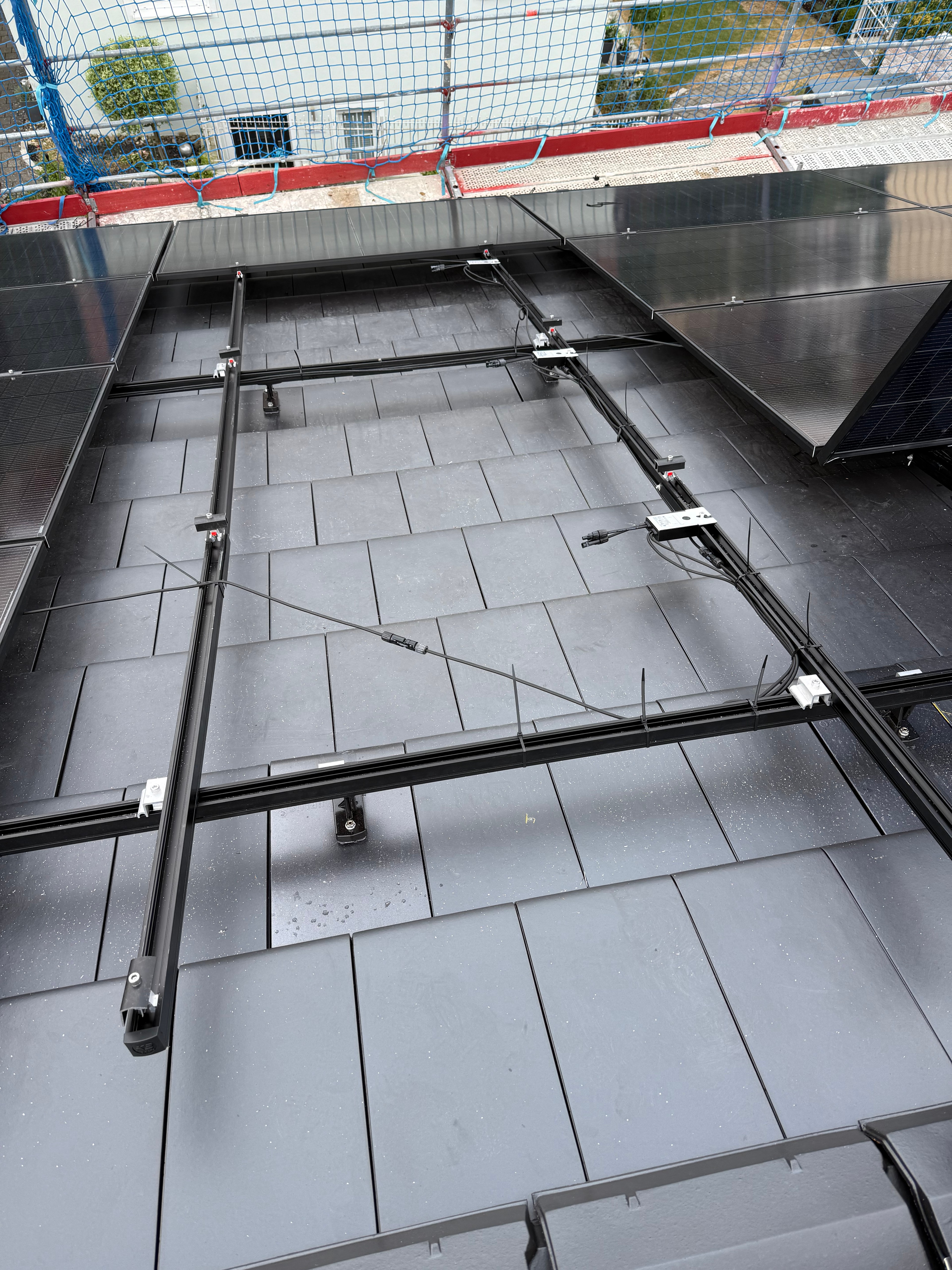 Kreuzschienen und erste Module auf anthrazitfarbenen Flachziegeln