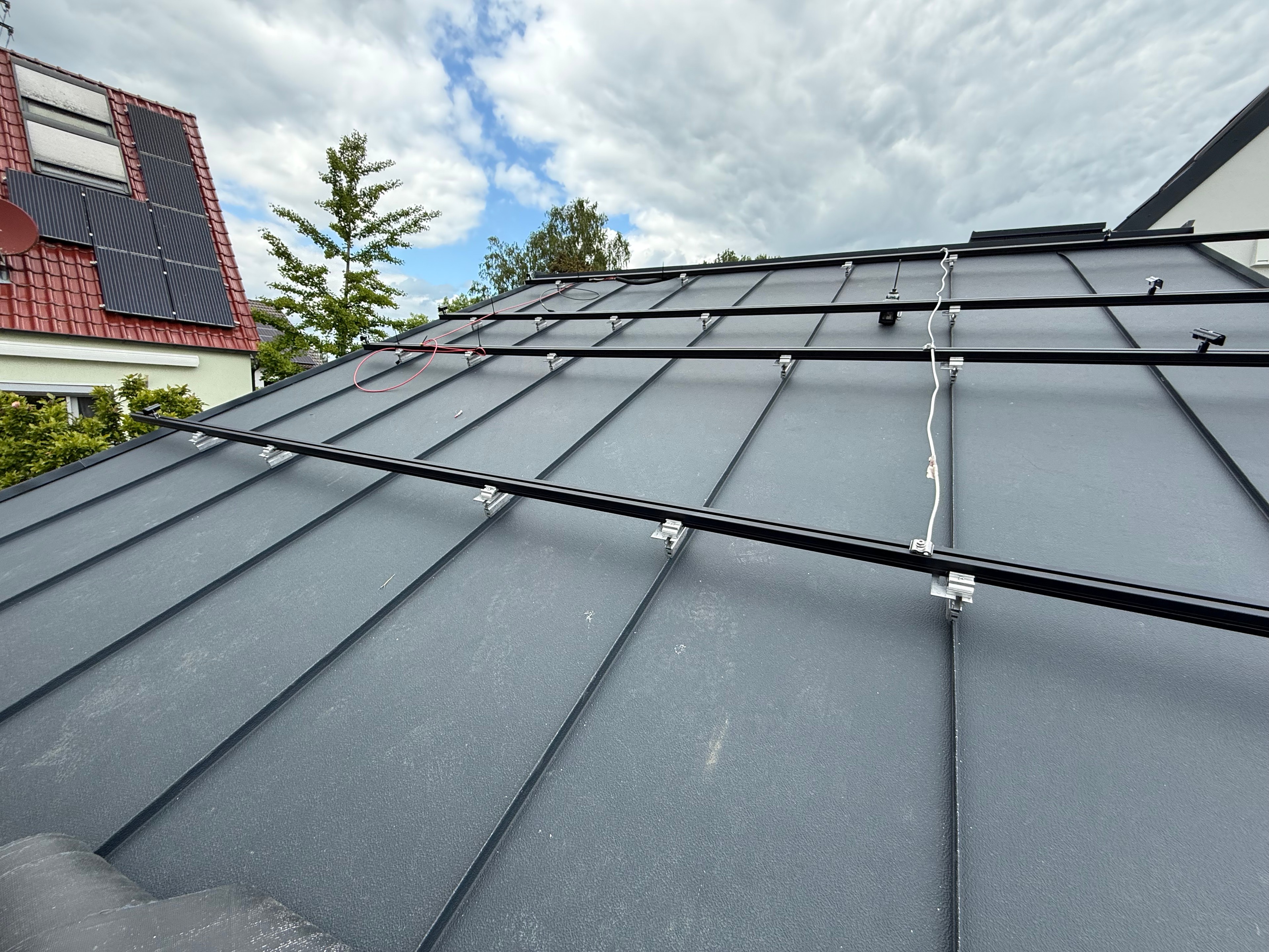 Schwarzes Schienensystem mit Klemmen auf einem Metalldach